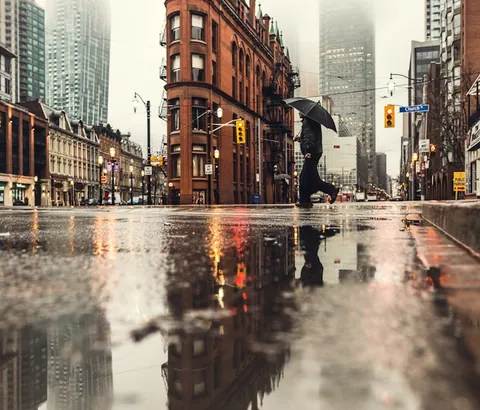 A rainy city street at dusk, reflections in the puddles.